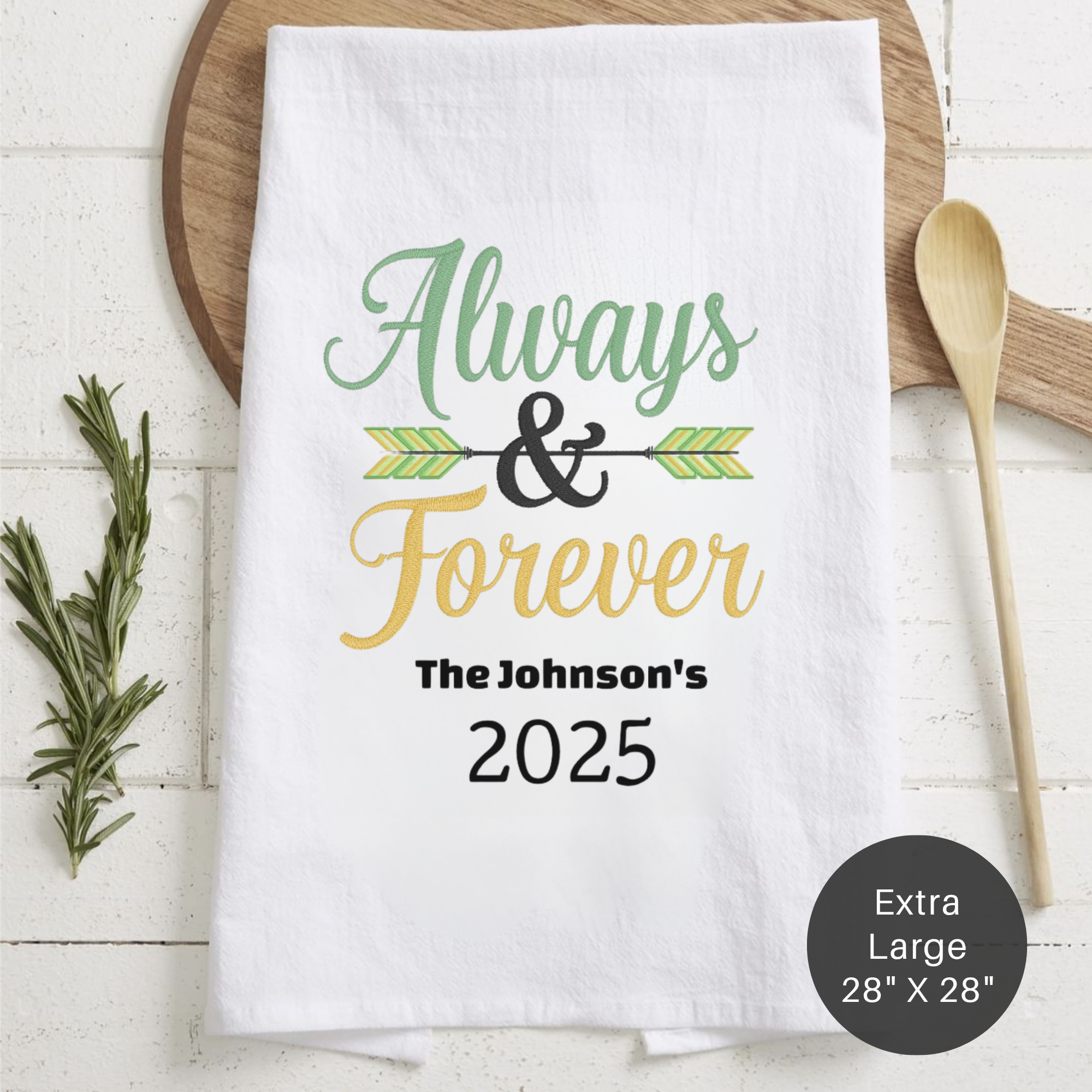 White folded tea towel with a Always & Forever personalized design laying on a counter.