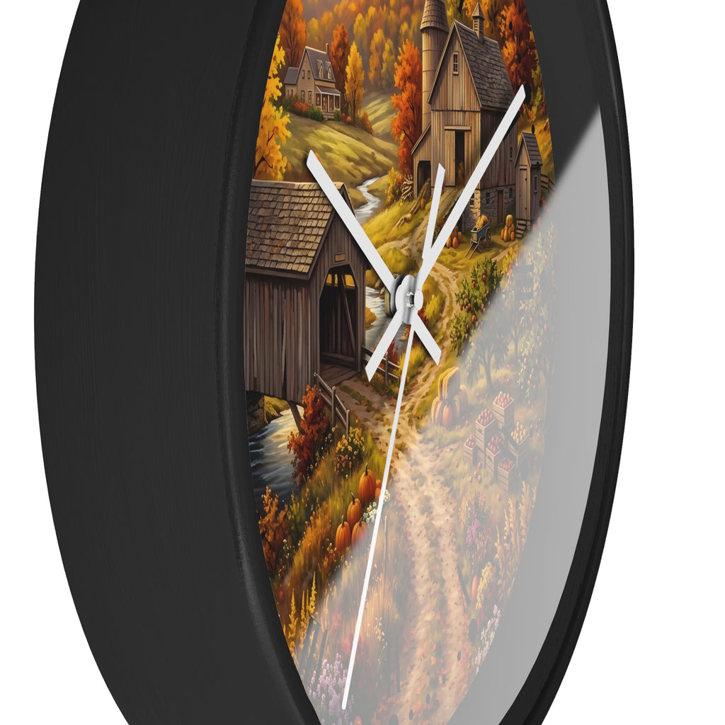 Round wall clock with a black frame and a printed autumn countryside scene featuring a bridge, barns, trees, and a winding path. The clock face has a reflective silver mirror-like section and white hands.