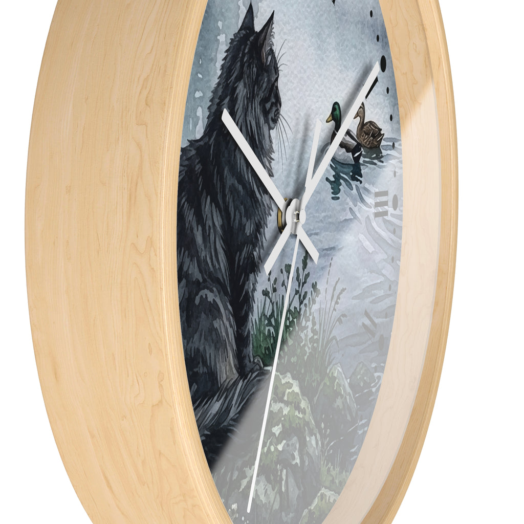Oval wall clock with a light natural wood frame and a printed artwork insert showing a black cat beside ducks in shallow water, with white clock hands.