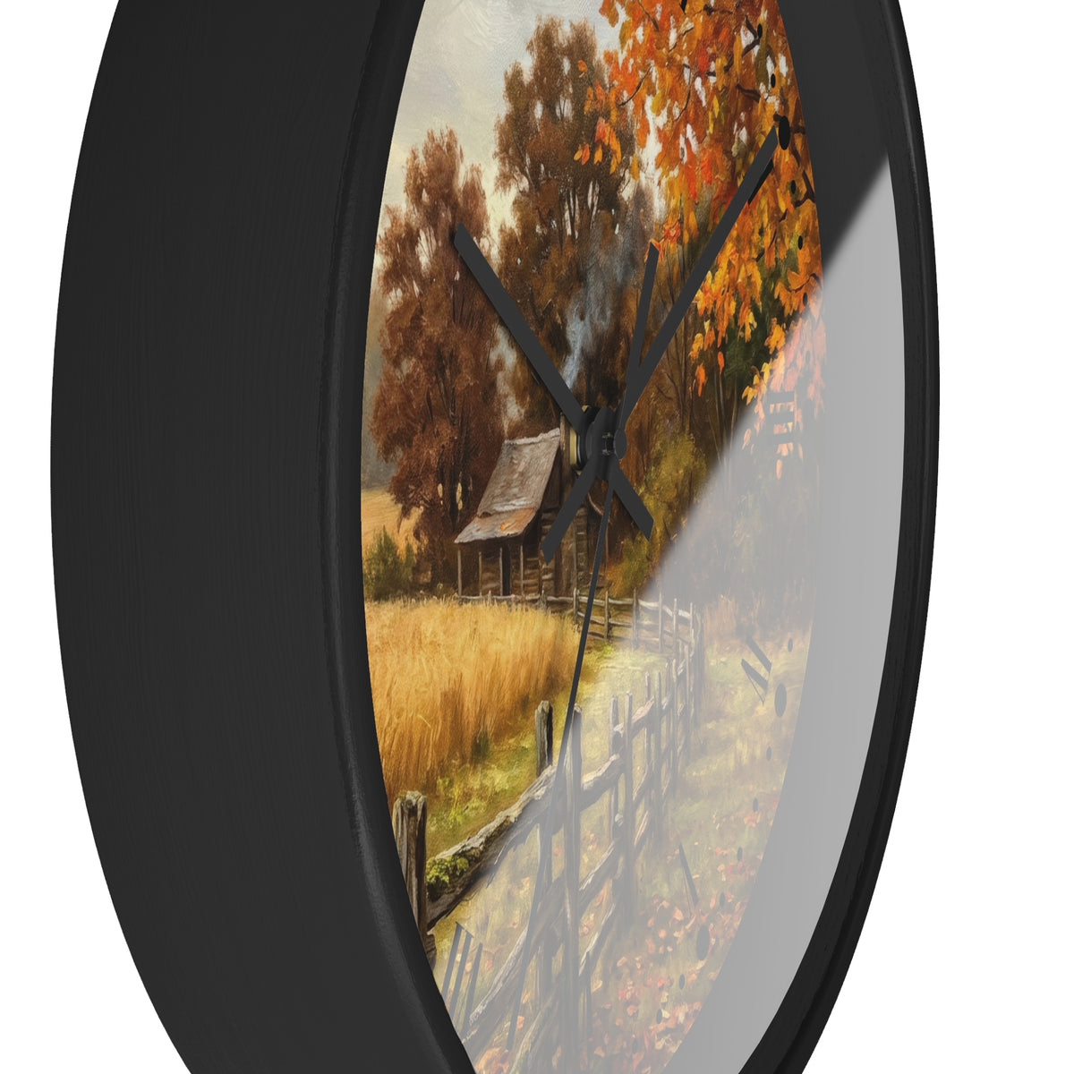 Round wall clock with a black frame and a printed autumn landscape design on the face, featuring orange and brown trees, a rustic cabin, and a fence, shown against a white background.