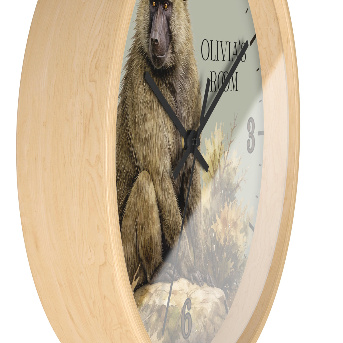 A round wall clock with a light natural wood frame and a printed dial showing a baboon illustration, with the text 'OLIVIA'S ROOM' and black numerals.