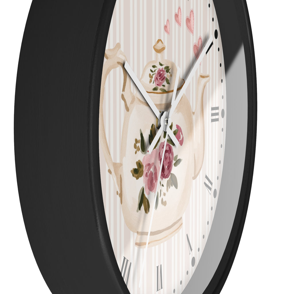 Round wall clock with a black frame and a white dial featuring a vintage floral teapot illustration and pink rose accents.