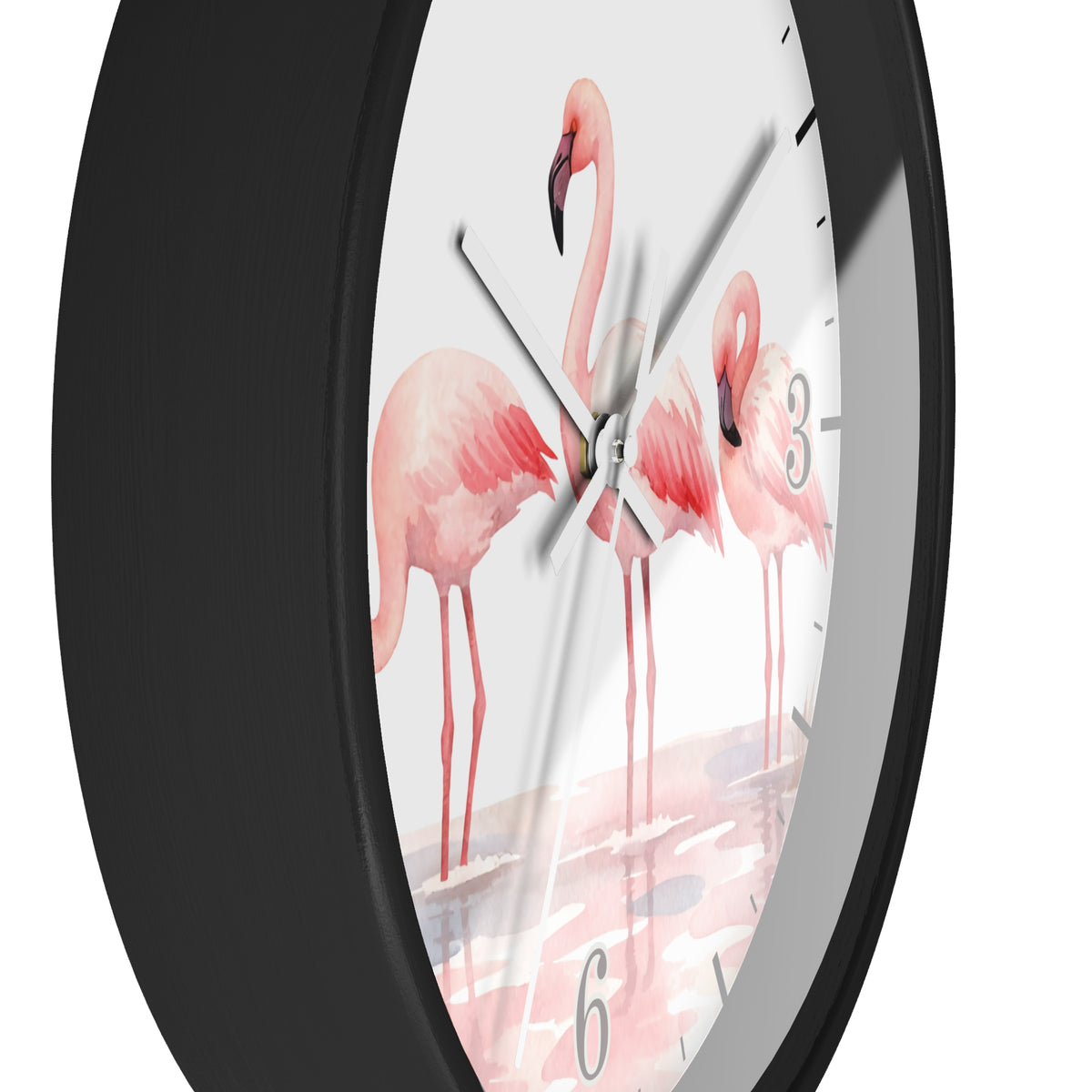 A close-up of a round wall clock with a matte black frame and a white dial printed with three pink flamingos standing in shallow water. The clock has black Arabic numerals and black hour markers, with silver-tone hands.