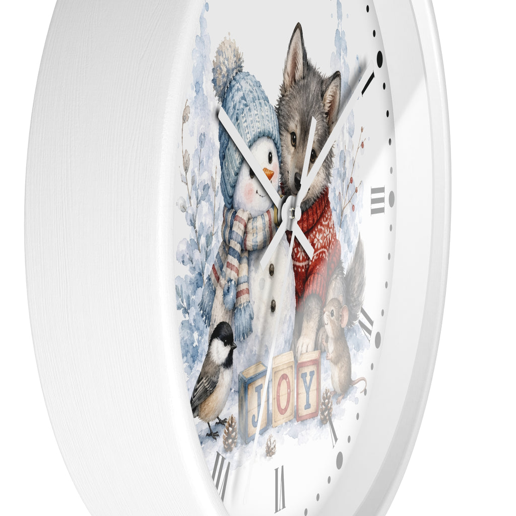 A round white wall clock with a winter-themed illustration on the face, showing a snowman, a wolf, a bird, and the word "JOY" in colorful blocks. The clock is photographed against a clean white background.