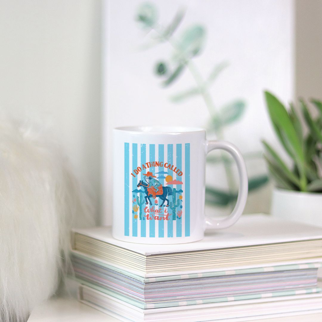 Mug with a striped cowboy frog design on a stack of books with a plant in the background