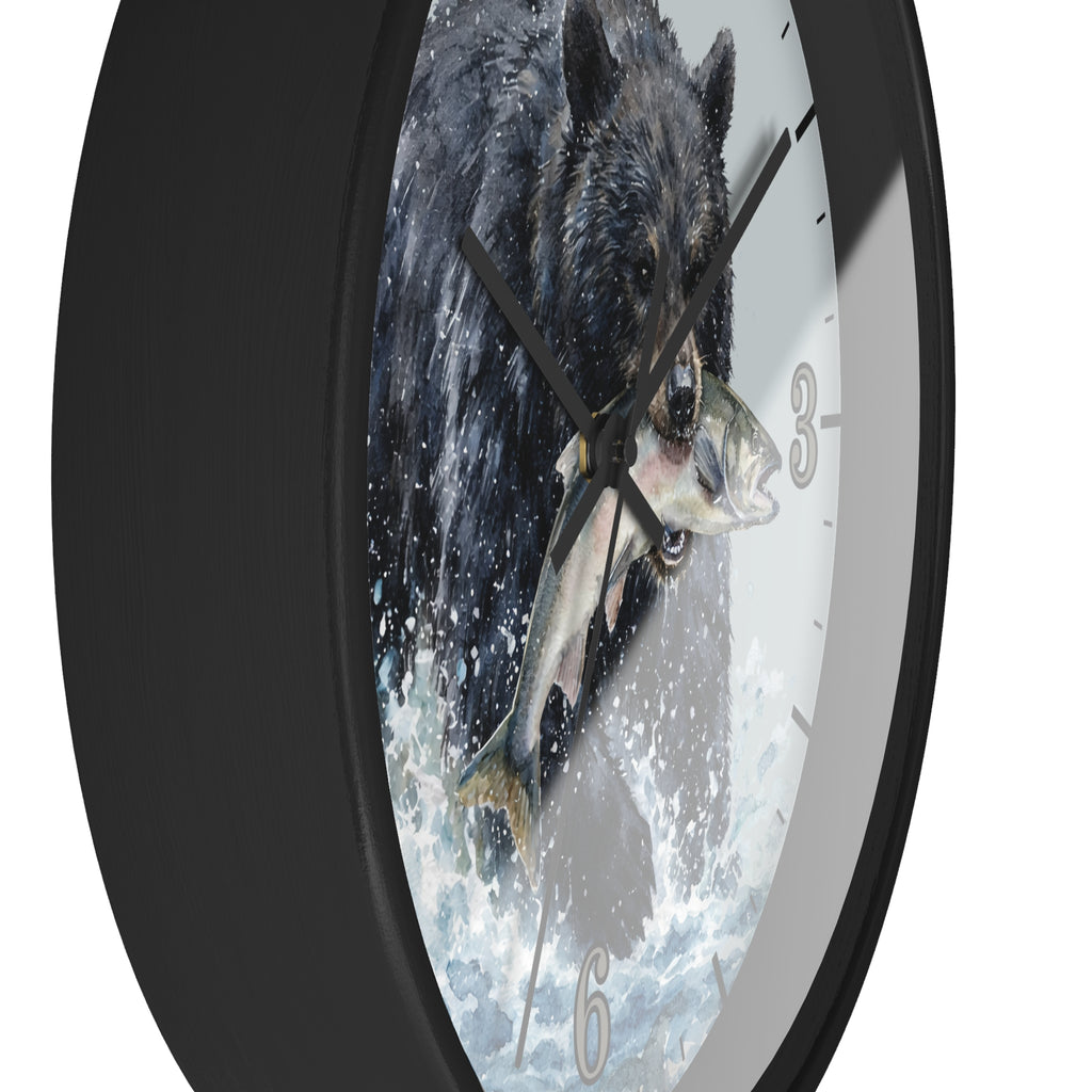 A round wall clock with a black frame and a printed face showing a black bear catching a fish in splashing water. The clock is shown at an angle against a plain white background.