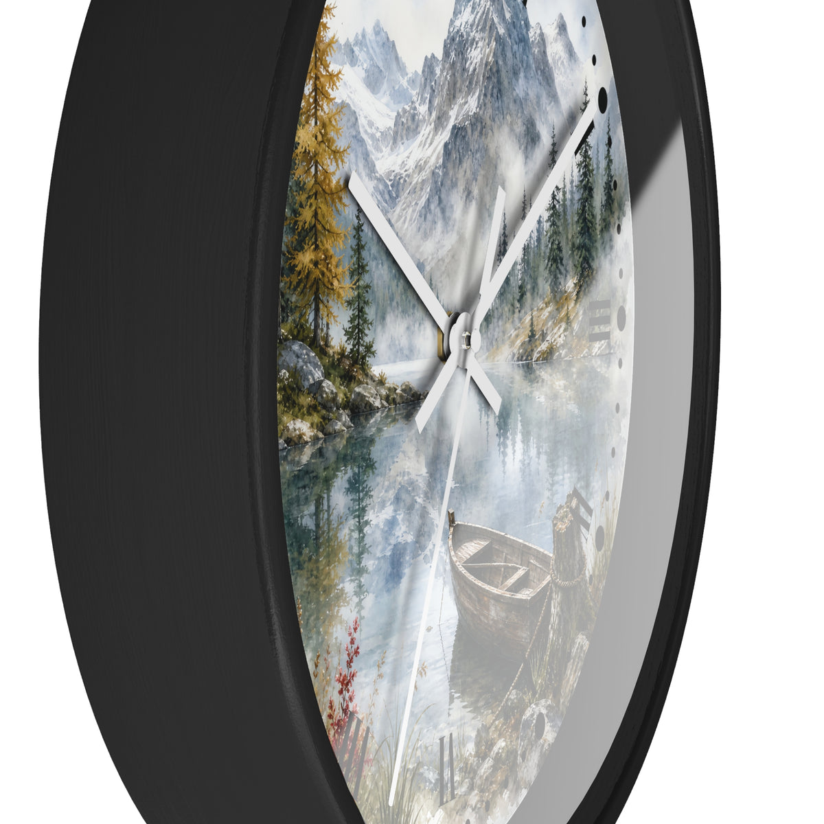 A round wall clock with a black frame and a scenic print of a mountain lake landscape featuring pine trees, a boat, and snowy peaks. The clock is shown at an angle against a plain white background.