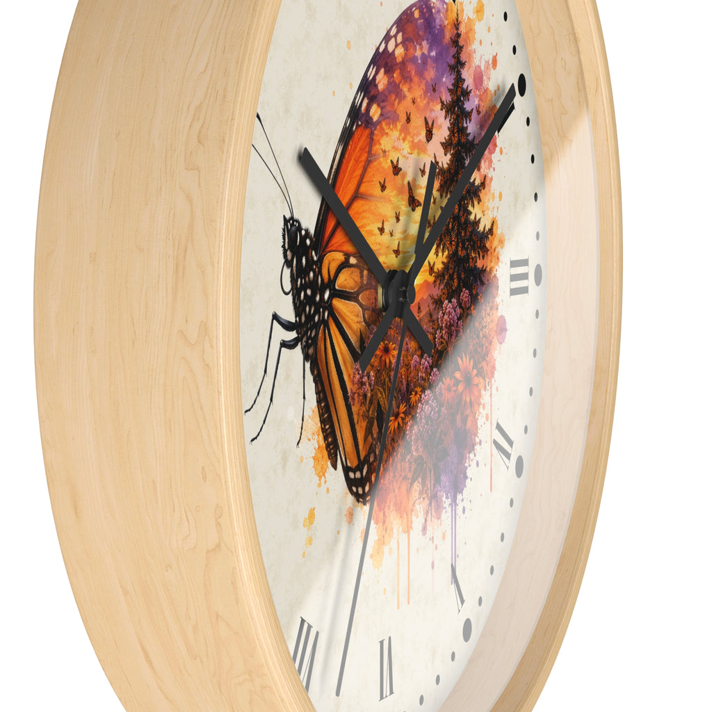 A close-up of a round wall clock with a light natural wood frame and a white dial featuring a large orange-and-black butterfly over a colorful watercolor sunset background.