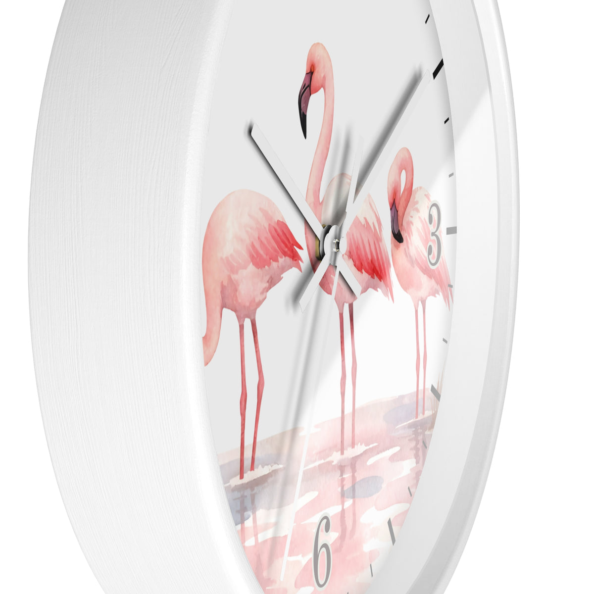 A white round wall clock featuring a watercolor-style illustration of three pink flamingos standing in shallow water, with black hour markers and silver hands.