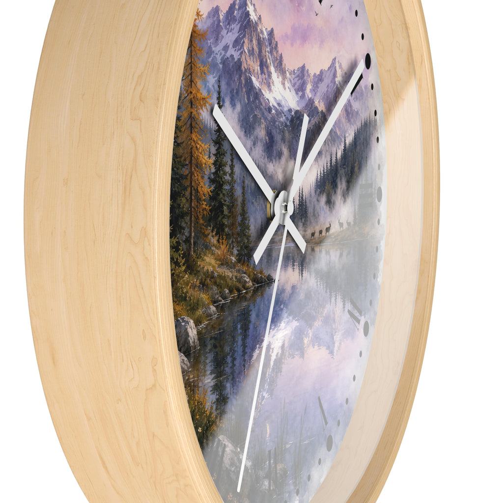 Round wall clock with a light natural wood frame and a scenic landscape print featuring mountains, a lake, trees, and a a herd of deer at dusk, shown on a white background.