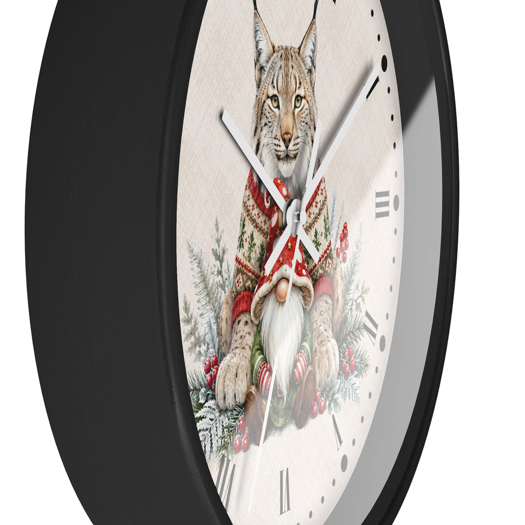 A round wall clock with a black frame and a cream-colored face featuring an illustration of a lynx wearing a red knit sweater and holding a gnome, set against a plain white background.