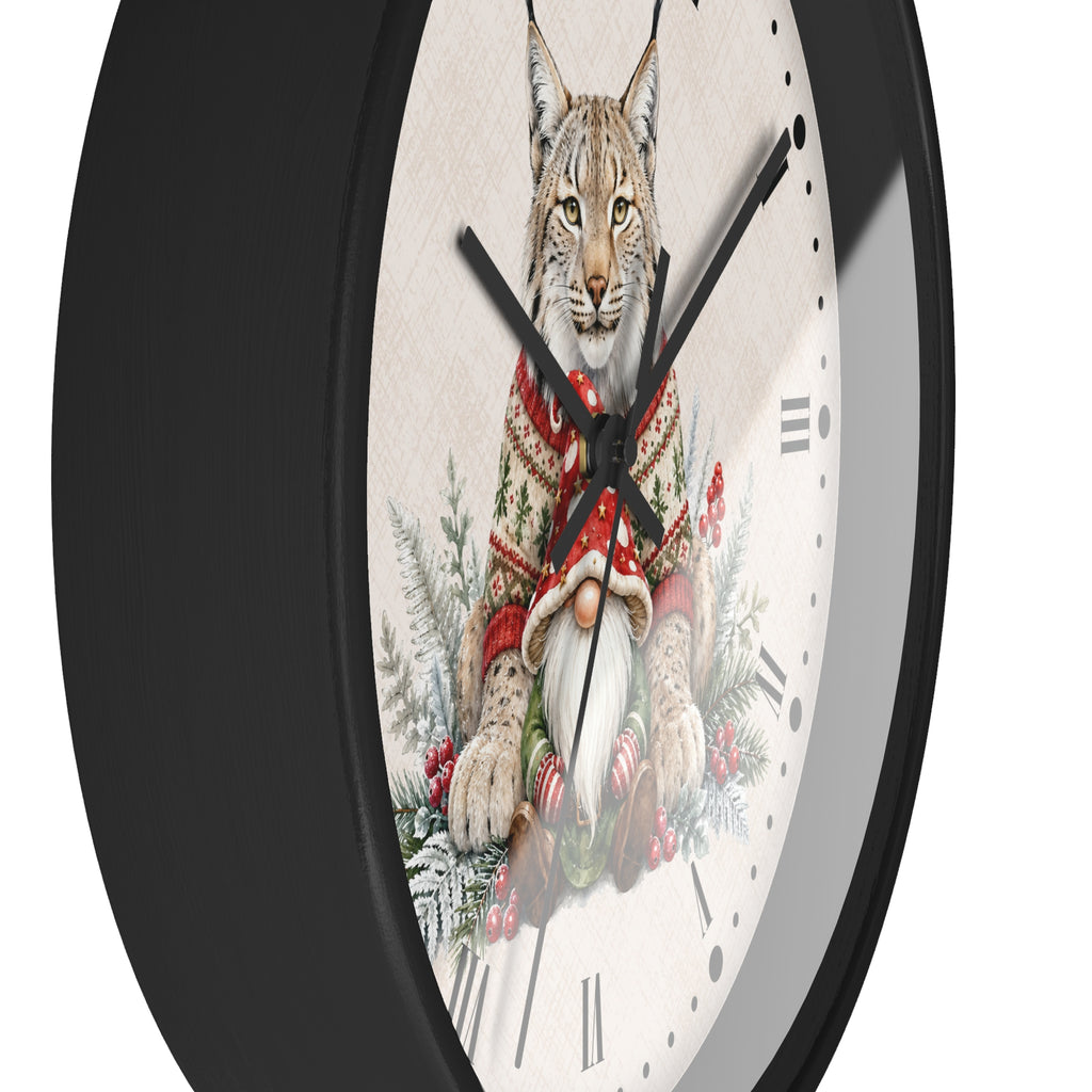A round wall clock with a black frame and a white face featuring an illustration of a lynx wearing a red knit sweater, surrounded by holiday greenery and a gnome.