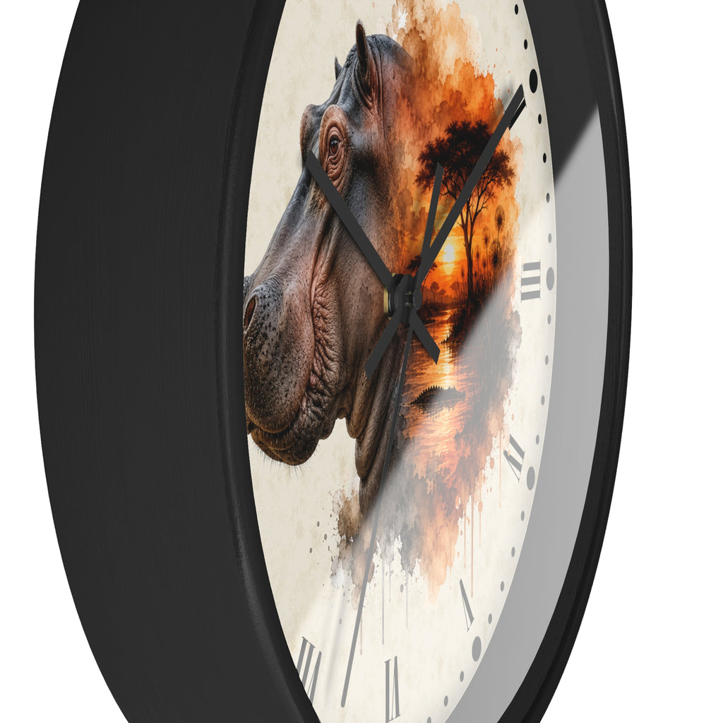 A round wall clock with a black frame and a white dial featuring a watercolor-style hippopotamus head and an orange sunset scene. The clock is shown at an angle against a plain white background.