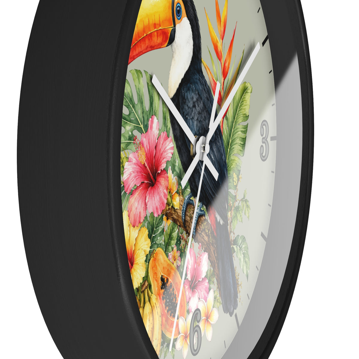 A close-up of a round wall clock with a black frame and a tropical design on the face, featuring a toucan, hibiscus flowers, and green leaves on a white background.