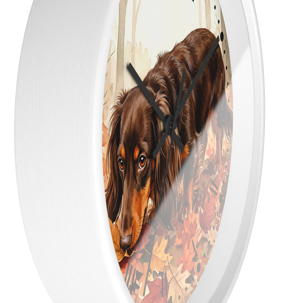 A round white wall clock featuring a printed illustration of a brown dachshund walking through autumn leaves, shown against a plain white background.