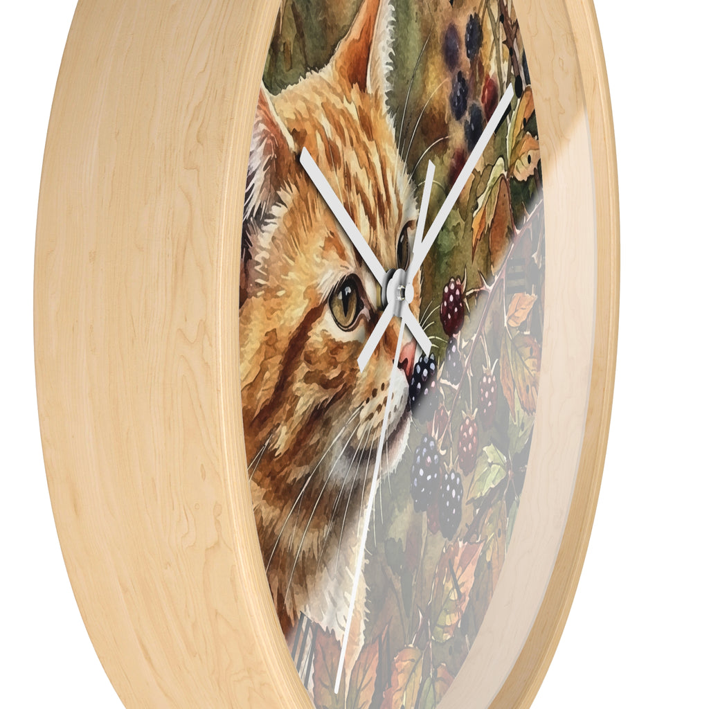 Round wall clock with a light natural wood frame and a printed illustration of an orange tabby cat over a background of leaves and blackberries, with white clock hands.