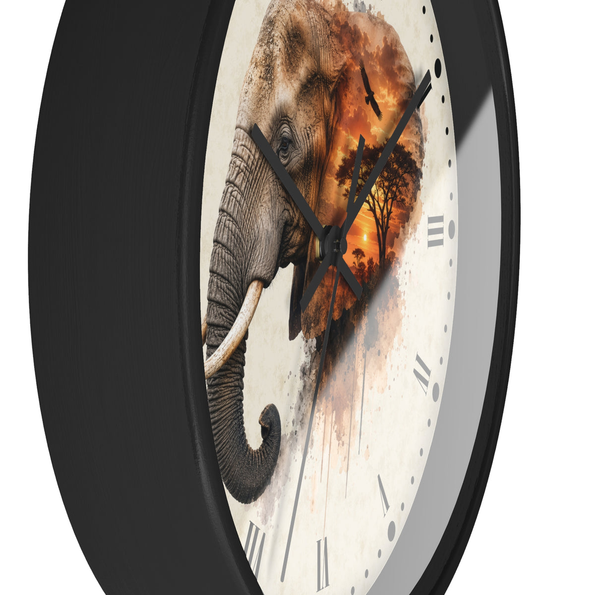 A round wall clock with a black frame and a cream-colored face featuring a detailed illustration of an elephant overlaid with an orange and brown sunset scene. The clock is shown at an angle against a plain white background.