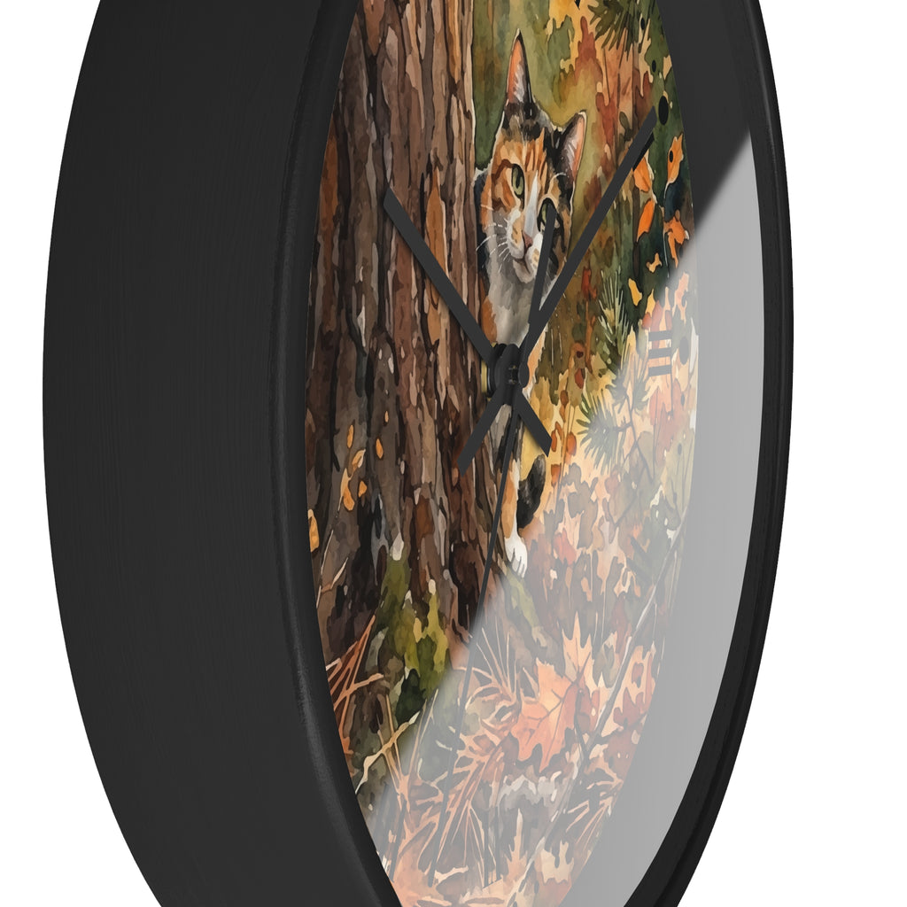 Round wall clock with a black frame and a printed autumn forest scene featuring a calico cat on the face, shown against a plain white background.