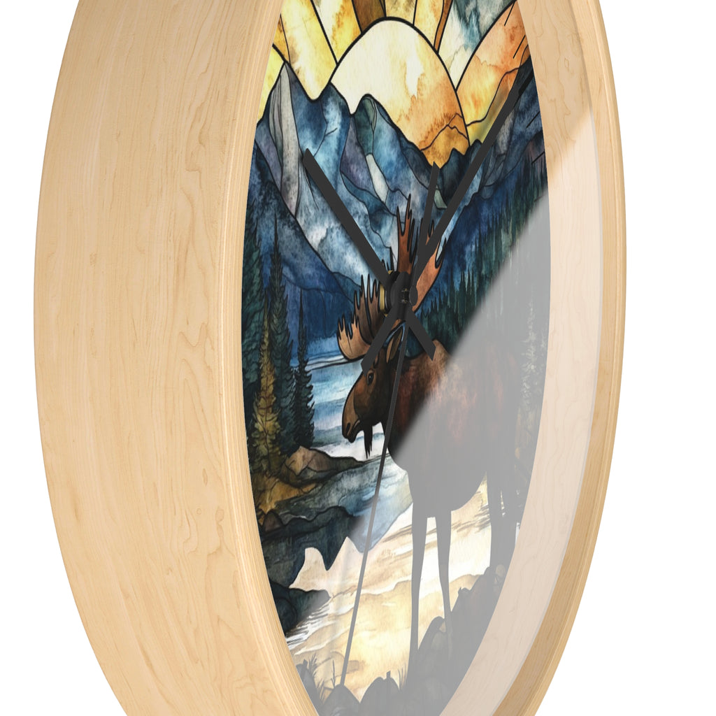 Oval wall clock with a light natural wood frame and a stained-glass-style artwork of a moose in a mountain landscape.