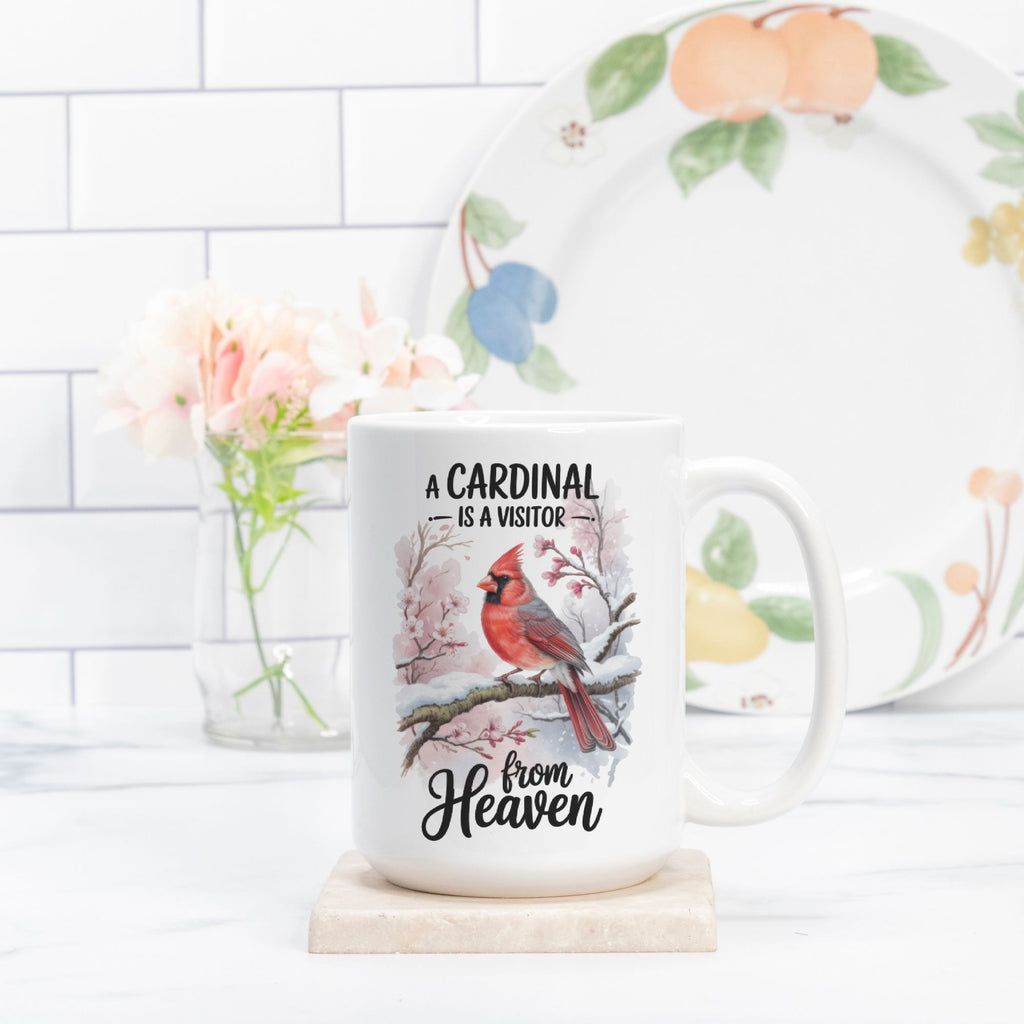 Mug with cardinal design and text on a white surface with a floral arrangement in the background