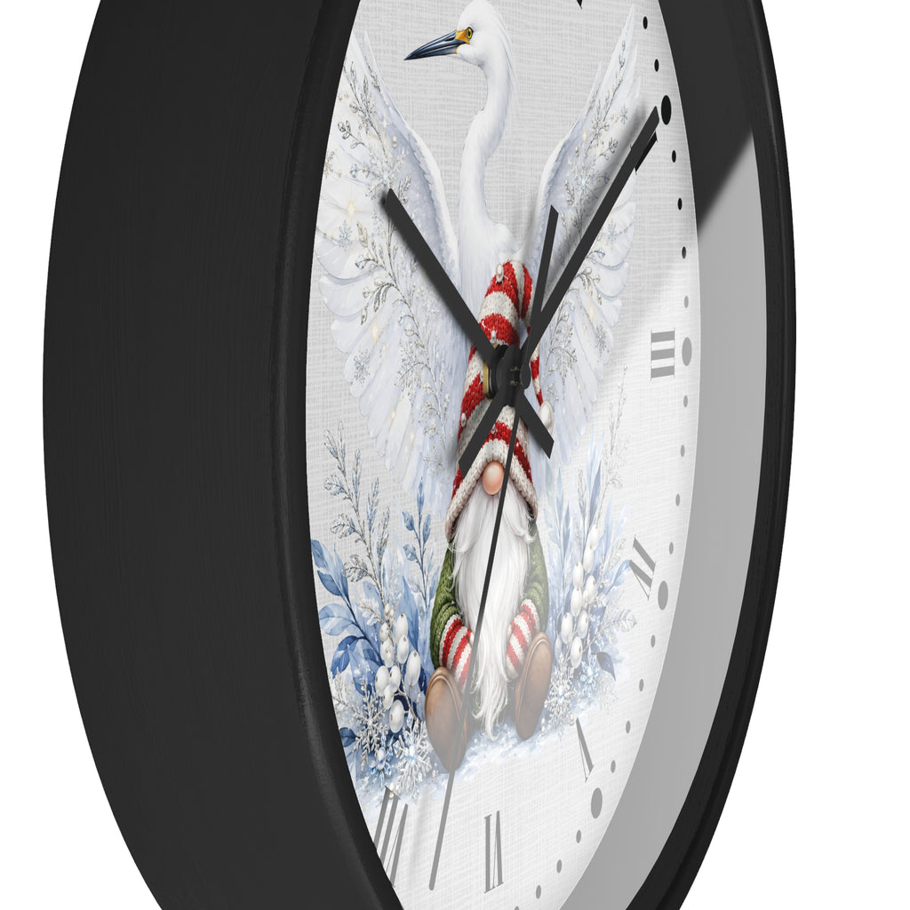 A close-up of a round wall clock with a black frame and a white face featuring a winter bird and gnome illustration, photographed against a light gray background.
