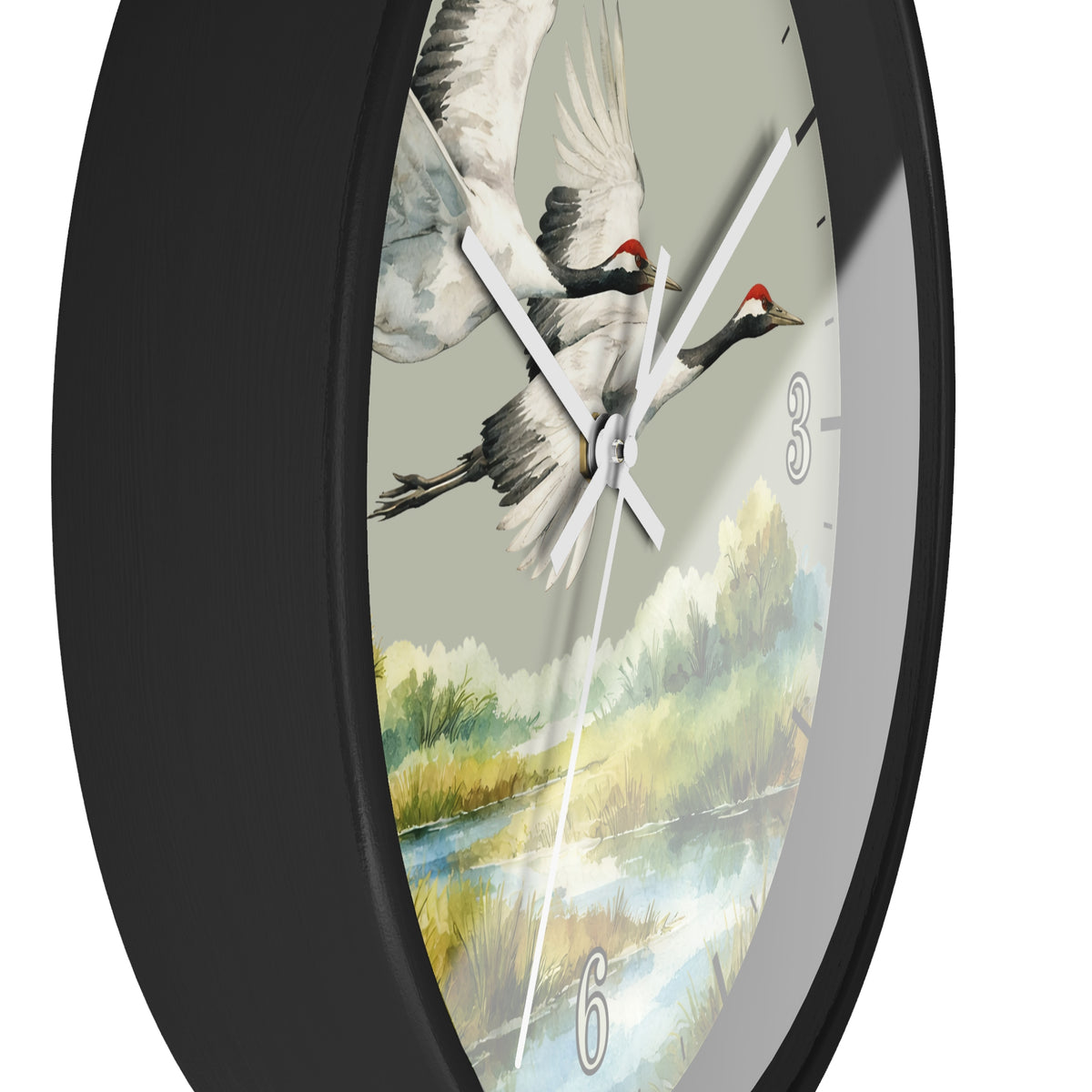 A close-up of a round wall clock with a black frame and a printed dial showing two flying cranes over a painted landscape. The clock has white hands and silver-tone numerals.