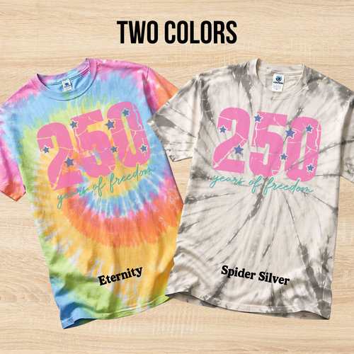 Two tie-dye t-shirts with '250 years of freedom' text on a wooden surface.