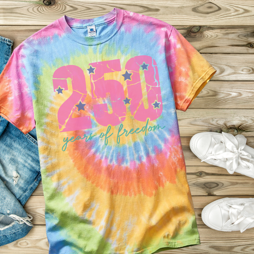 Colorful tie-dye t-shirt with '250 years of freedom' text on a wooden surface.