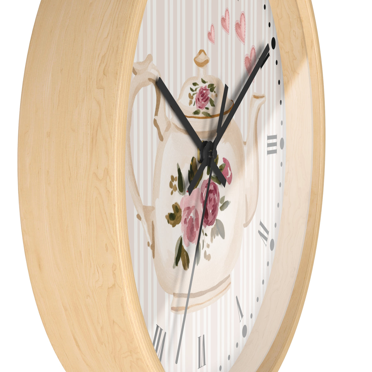 Round wall clock with a light natural wood frame and a white dial featuring a vintage teapot illustration with pink roses and black hands.