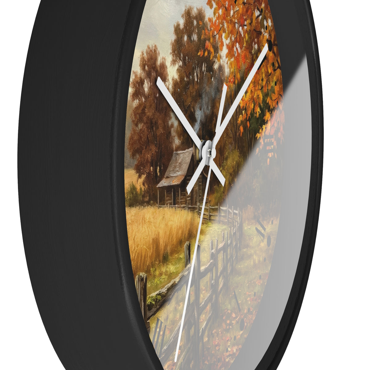 Round wall clock with a black frame and a printed autumn landscape design on the face, featuring orange and brown trees, a rustic cabin, and a fence. The clock is shown against a plain white background.