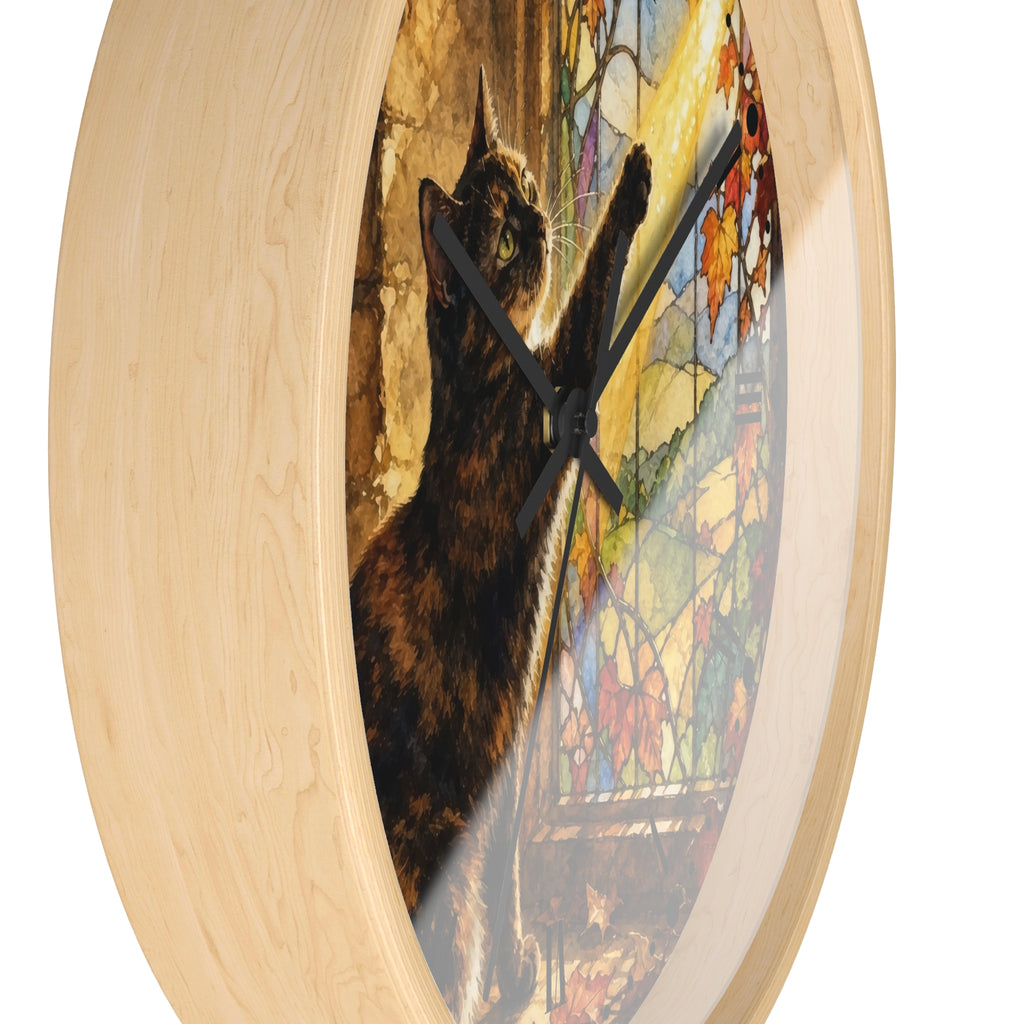 Round wall clock with a light natural wood frame and a printed artwork of a dark brown cat reaching toward a colorful stained-glass window. The clock is shown at an angle against a plain white background.