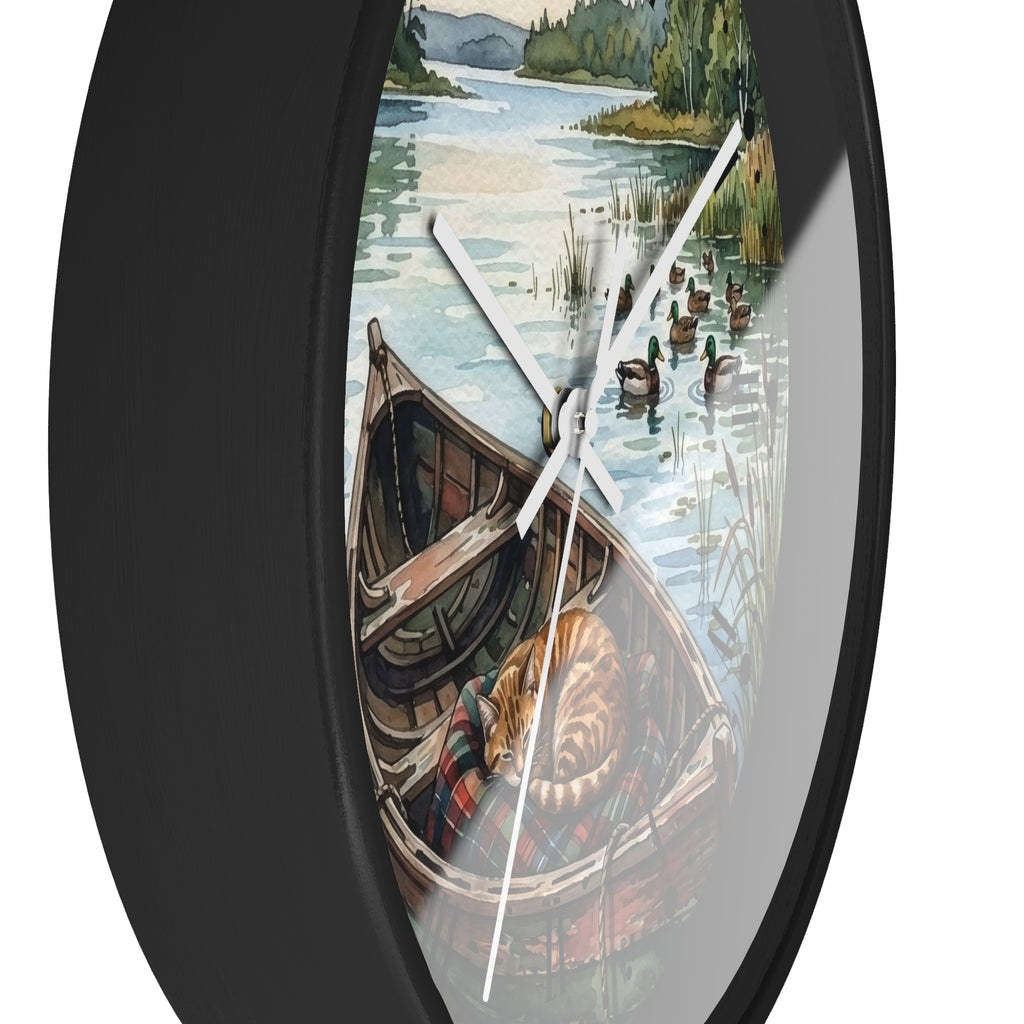Round wall clock with a black frame and a printed scenic illustration of a lake, ducks, shoreline, and a canoe, shown against a plain white background.
