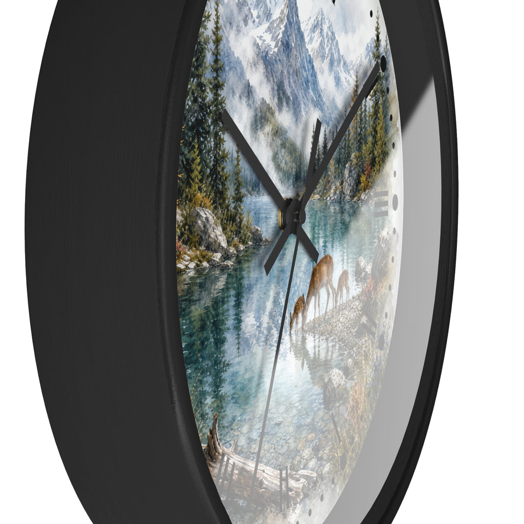 A round wall clock with a black frame and a scenic landscape print featuring a mountain lake, evergreen trees, and deer, shown against a plain white background.
