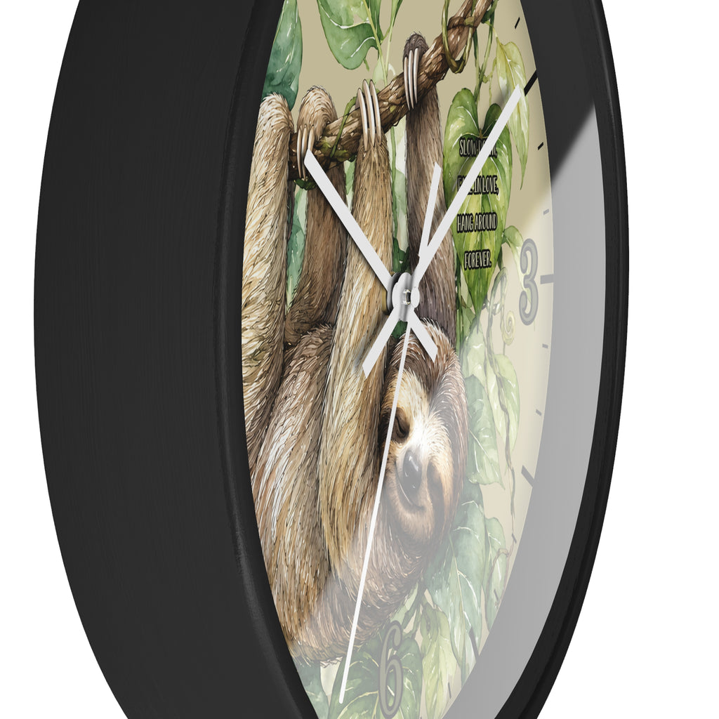 A round wall clock with a black frame and a printed face showing a sloth hanging from a tree branch with green leaves. The clock is photographed against a plain white background.