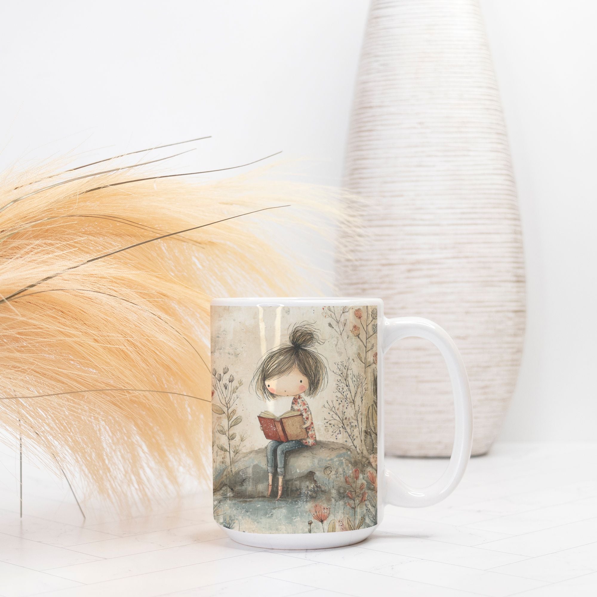Mug with a design of a girl reading a book on a stone, placed on a light surface with decorative elements.