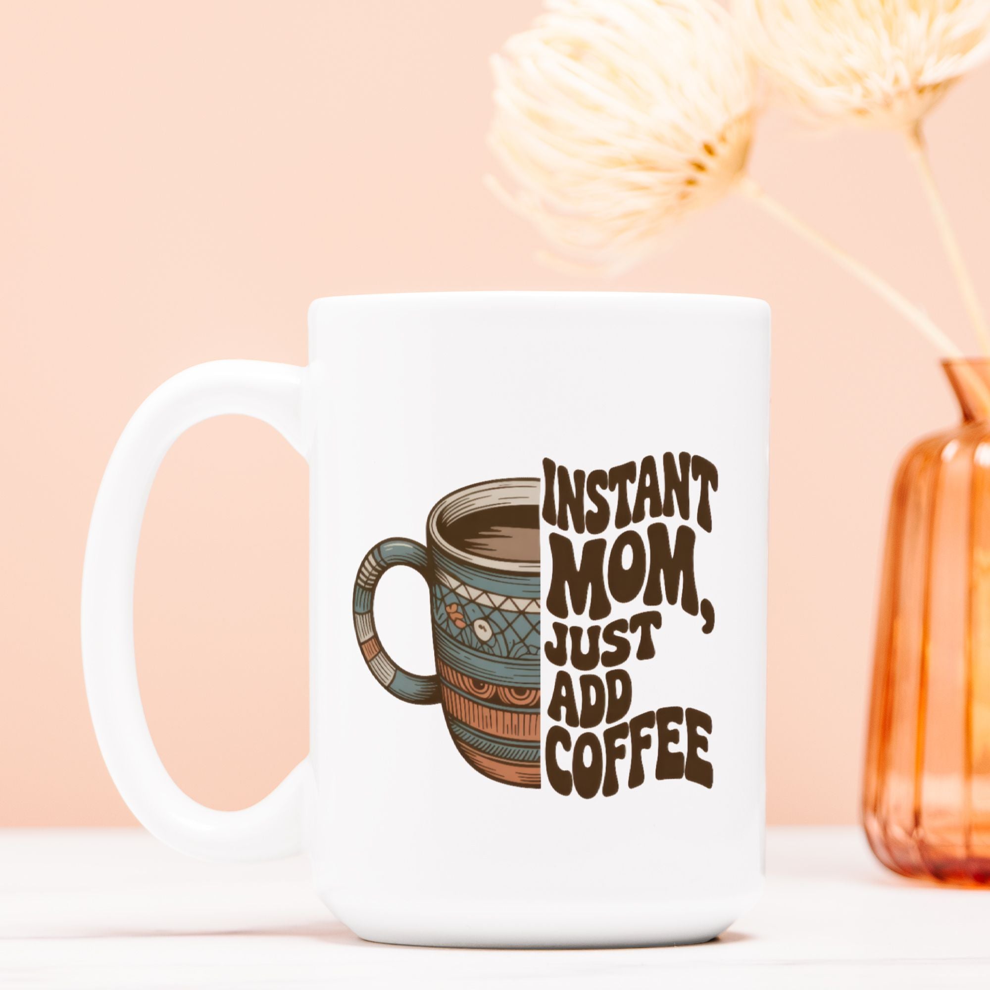 White mug with a design of a coffee cup and text 'Instant Mom, Just Add Coffee' on a light pink background.