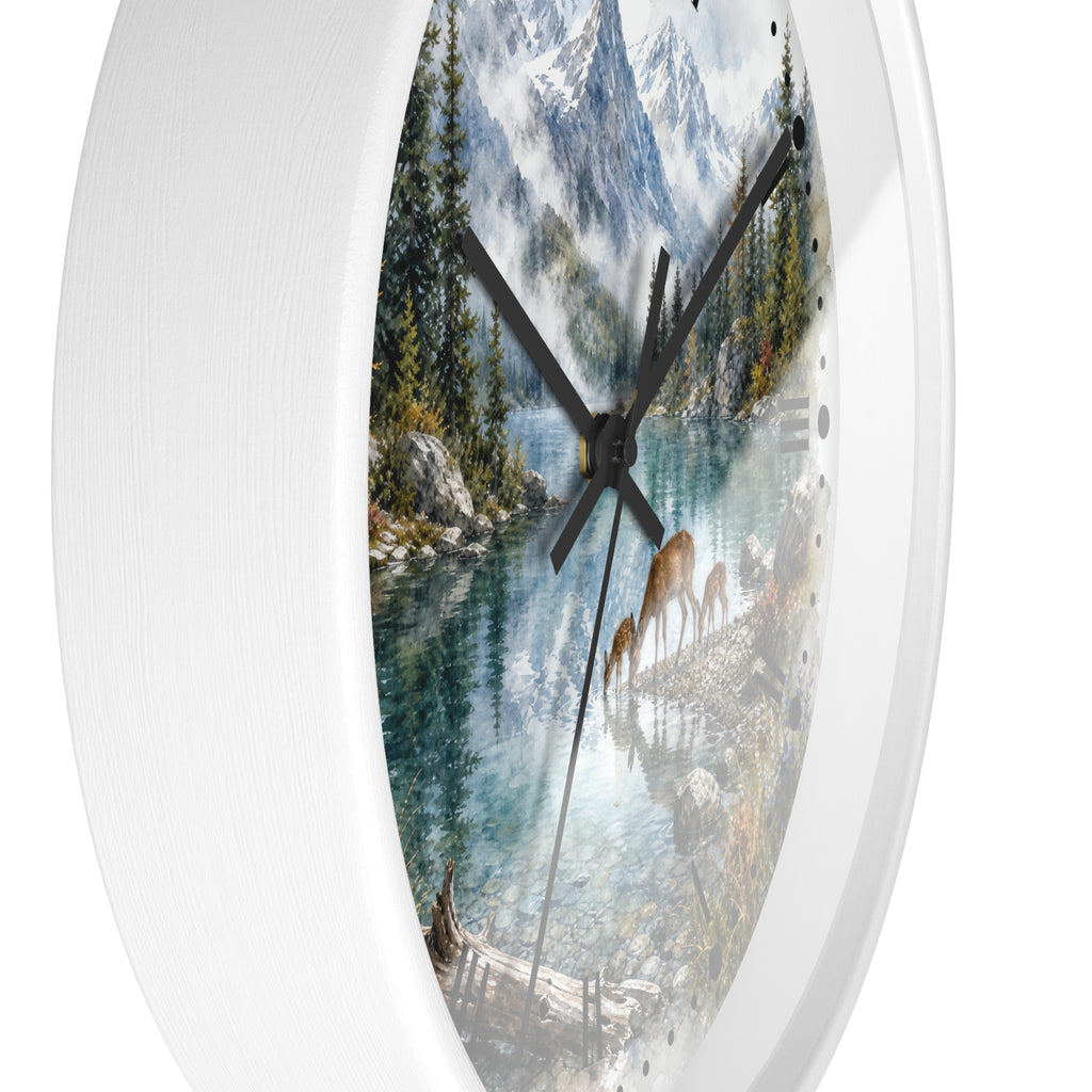 A round wall clock with a white frame and a scenic landscape print featuring a mountain lake, evergreen trees, and deer, shown against a plain white background.