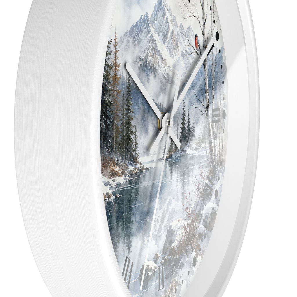 A round white wall clock with a printed winter landscape face showing snow-covered mountains, trees, and a frozen river, photographed against a plain white background.