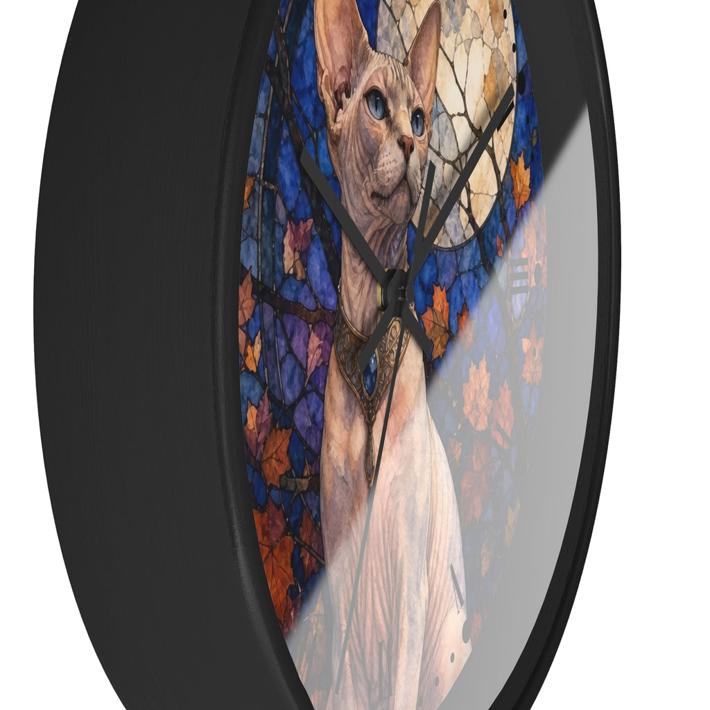 A round wall clock with a black frame and a printed design of a Sphynx cat in front of a stained-glass-style moon and autumn leaves.