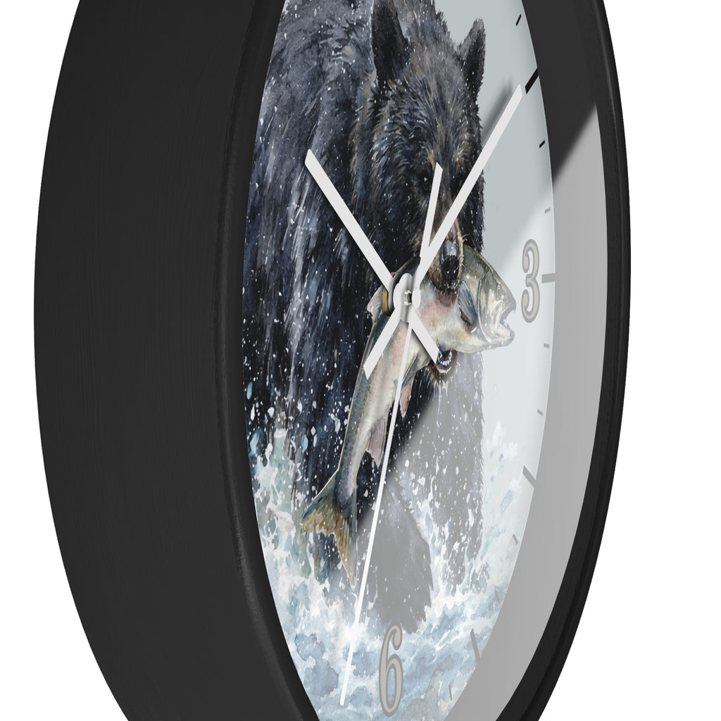 A round wall clock with a black frame and a printed face showing a black bear catching a fish in splashing water. The clock is photographed against a plain white background.