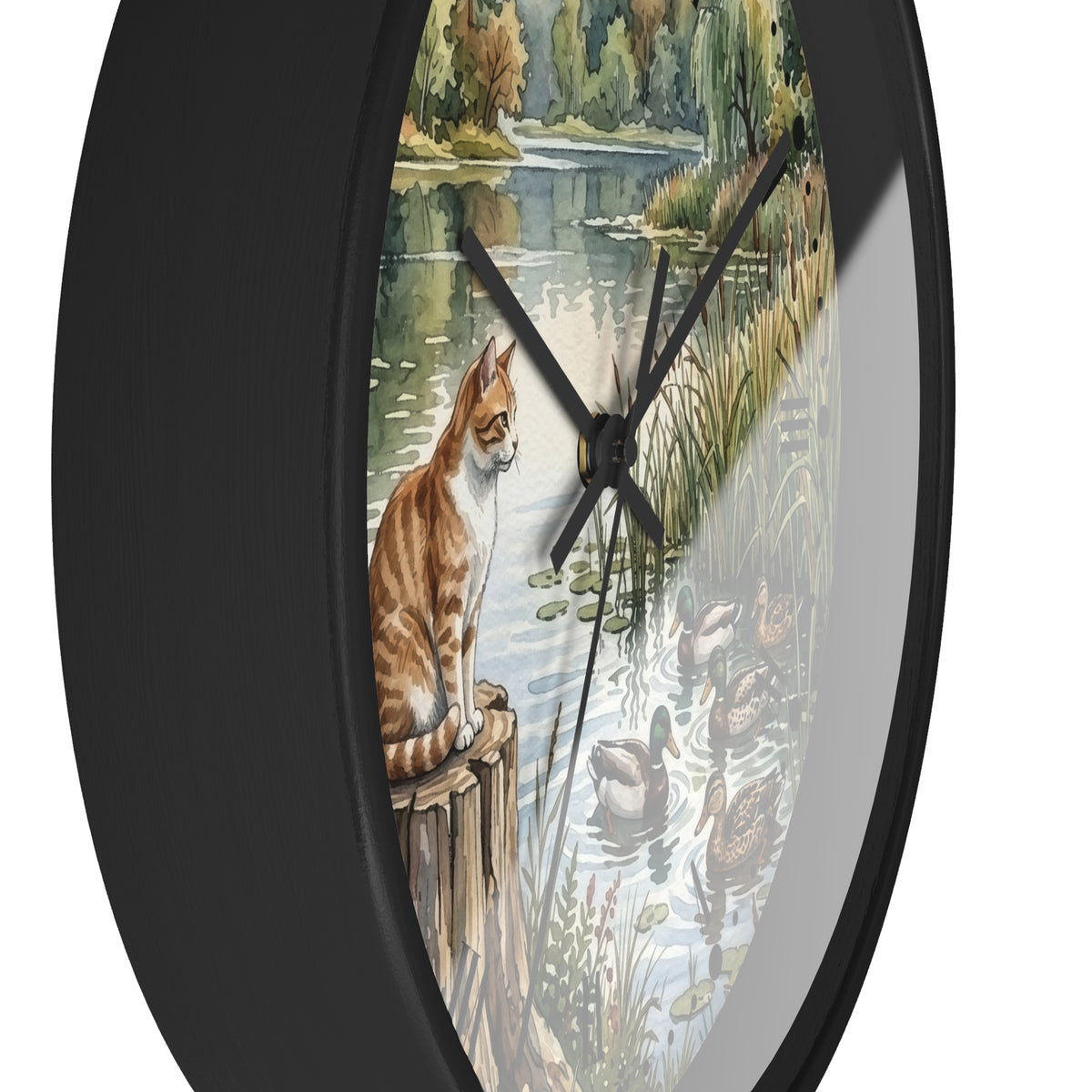 Round wall clock with a black frame and a printed scenic face showing an orange tabby cat sitting by a pond with ducks, on a white background.