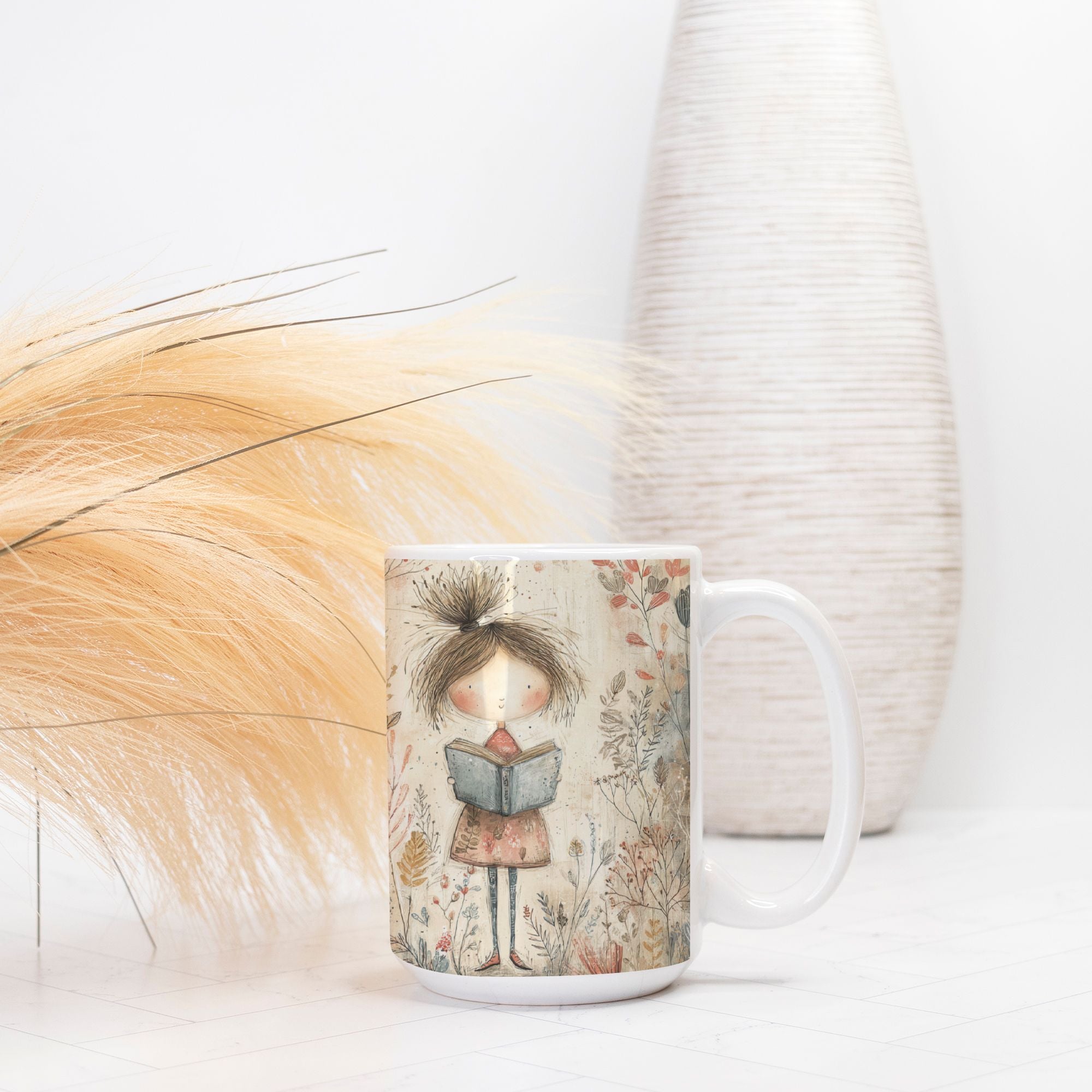 Mug with a design of a girl reading a book, placed on a surface with a vase and decorative elements in the background.