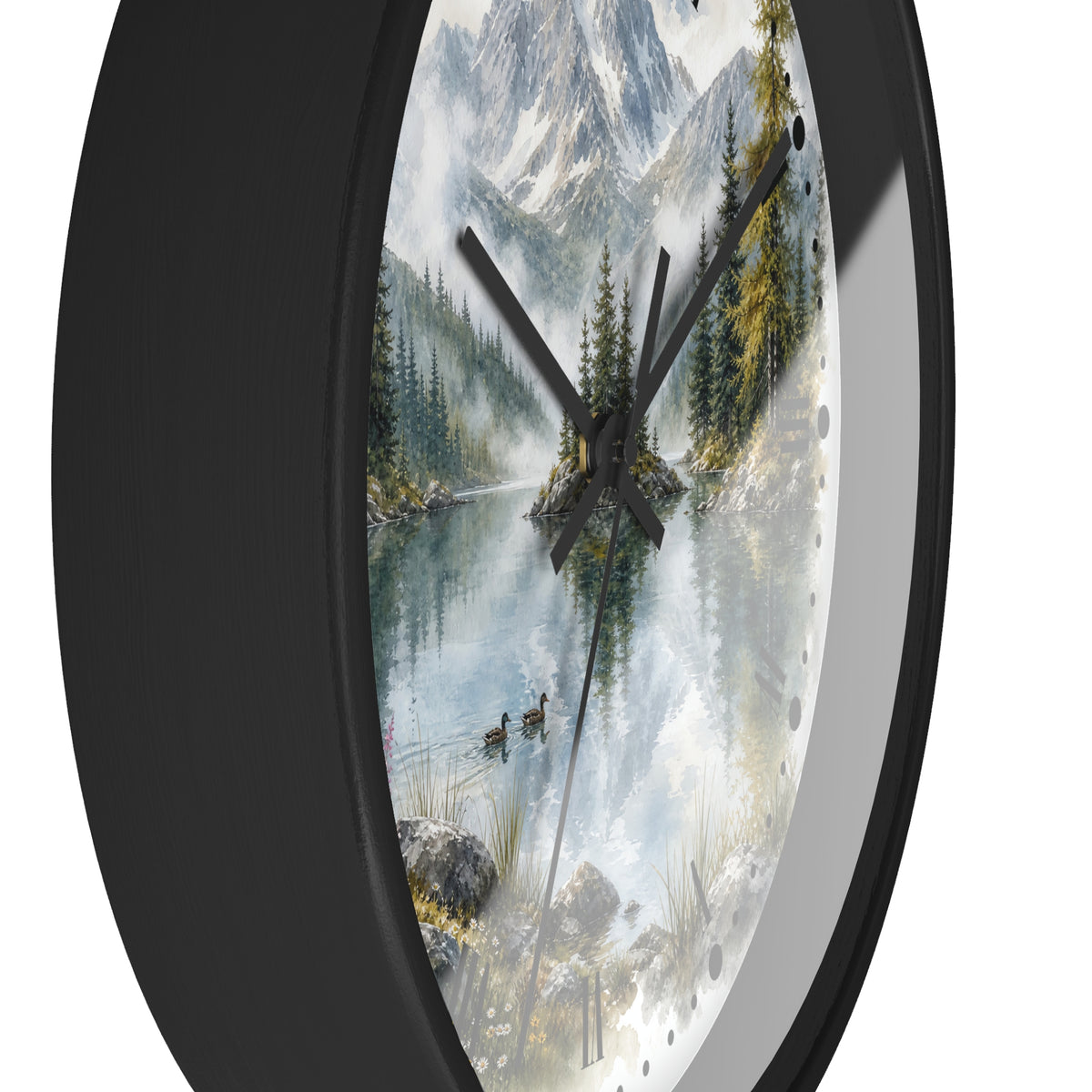 A round wall clock with a black frame and a scenic landscape print on the face, showing a misty mountain lake with pine trees, ducks, and snow-capped peaks. The clock is photographed against a plain white background.