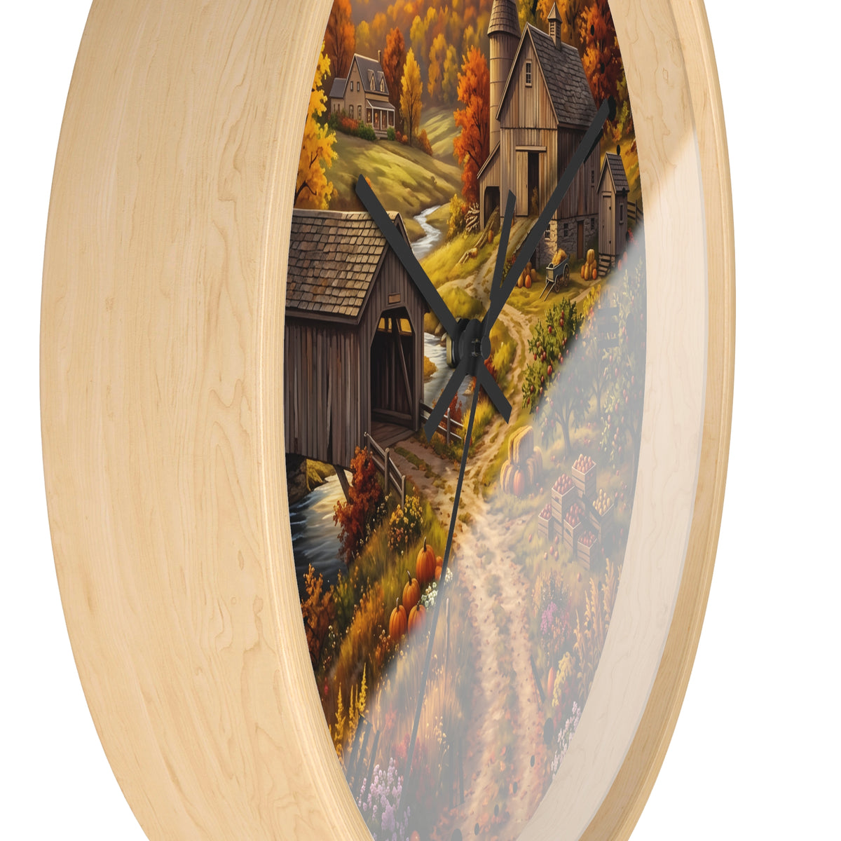 Round wall clock with a light natural wood frame and a printed autumn landscape design featuring a covered bridge, rustic house, trees, and a winding path. Black clock hands are visible against a plain white background.