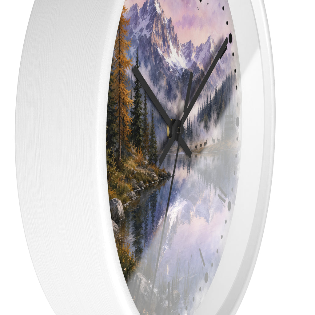 Round wall clock with a white textured frame and a scenic print featuring mountains, pine trees, and a reflective lake, and a herd of deer at dusk shown against a plain white background.
