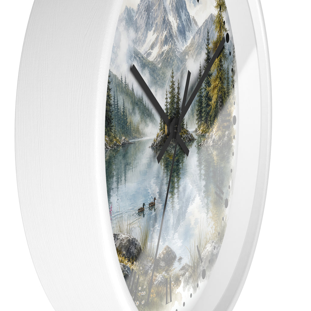 A white oval wall clock featuring a scenic print of a misty mountain lake with pine trees, ducks, and snow-capped peaks, with black hands and small black dot hour markers.