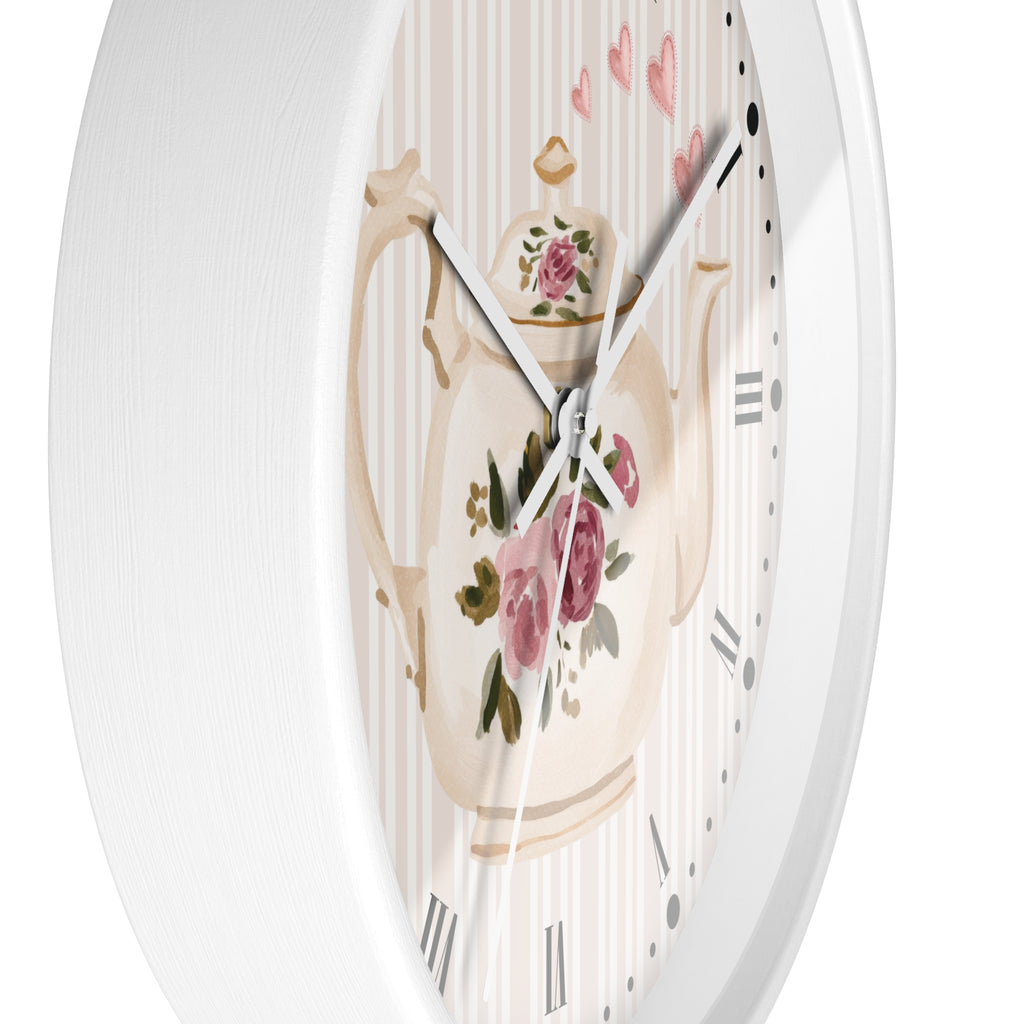 Round wall clock with a white frame and a decorative dial featuring a cream teapot with pink roses, green leaves, and a striped background with small pink hearts.