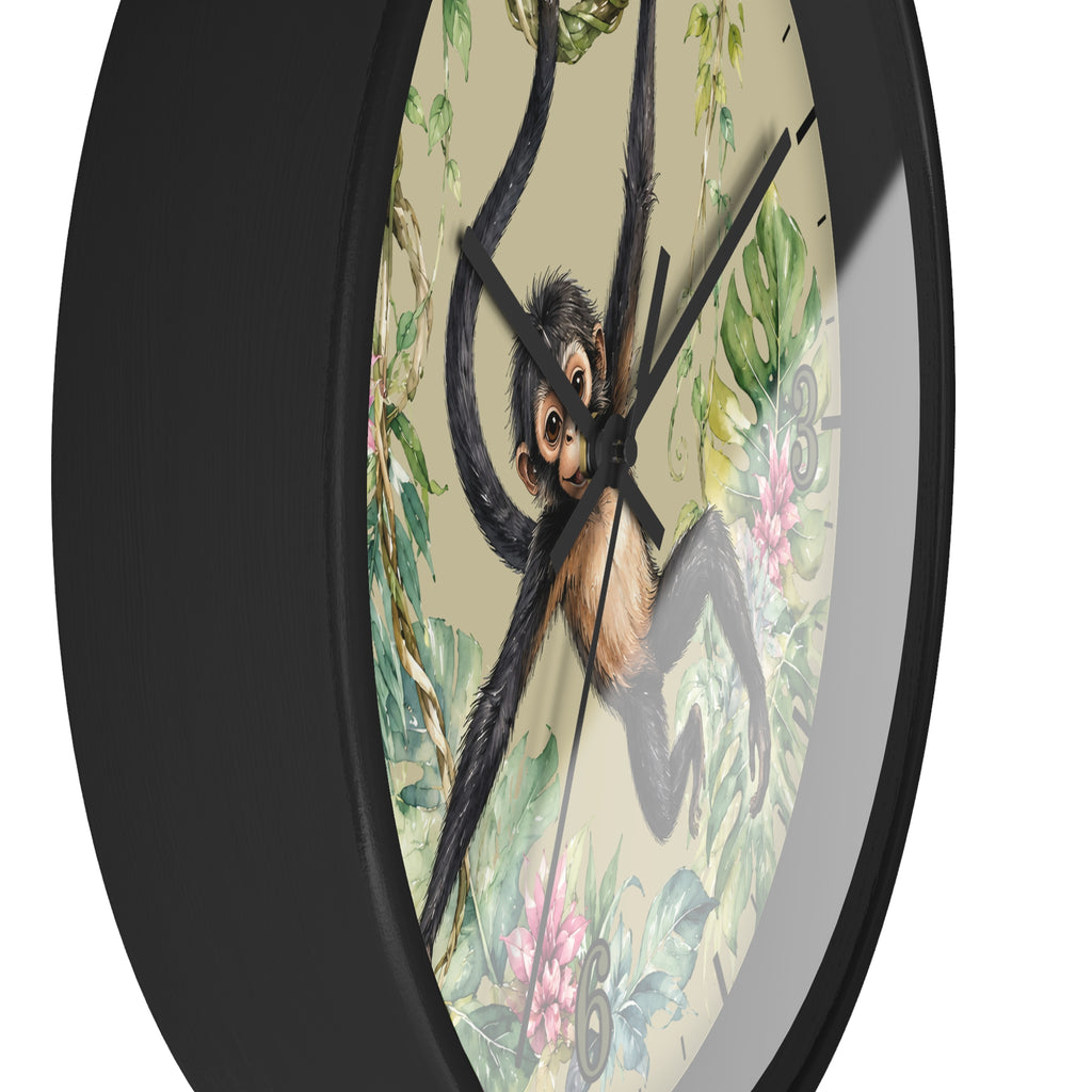 A close-up of a round wall clock with a black frame and a tropical jungle design featuring a hanging spider monkey, green leaves, and pink flowers on a light beige background.