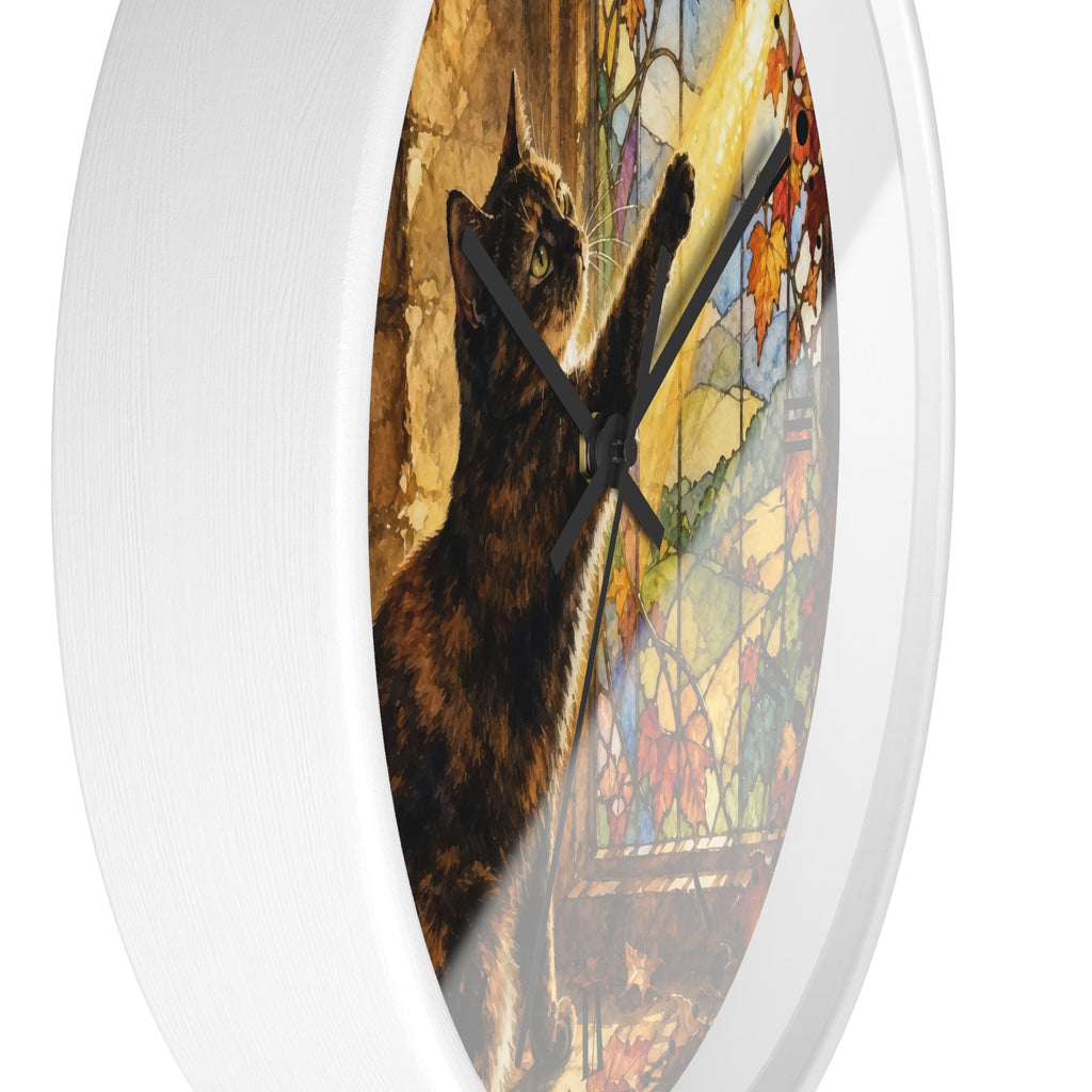 A white round wall clock with a printed cat artwork on the face. The design shows a dark brown cat in front of a colorful stained-glass window, with black clock hands.