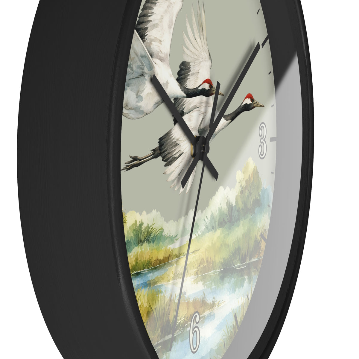 A close-up of a round wall clock with a black frame and a printed dial showing two flying cranes over a landscape. The clock has black hands and white numerals.